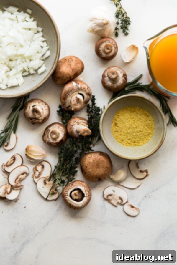 Easy Vegan Mushroom Gravy - a flavorful vegan mushroom gravy that comes together in less than 30 minutes and pairs perfectly with holiday or everyday meals! #vegan #glutenfree #gravyrecipe #holidayrecipes Fresh ingredients for vegan mushroom gravy laid out on a marble surface, including cremini mushrooms, onion, garlic, and herbs