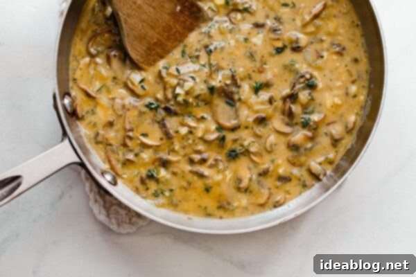 Velvety Vegan Mushroom Gravy 7 Vegan mushroom gravy thickening in a skillet, stirred with a wooden spoon