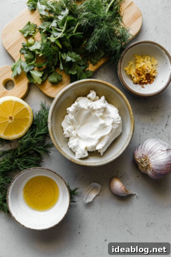 Whipped Garlic Herb Goat Cheese 5 Fresh ingredients for Garlicky Herbed Goat Cheese Spread laid out on a wooden board