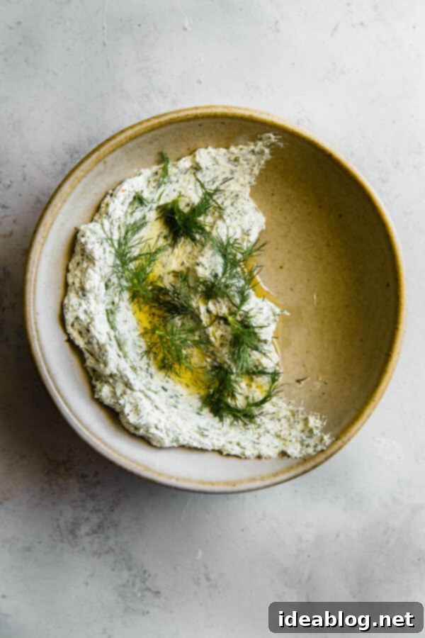 Whipped Garlic Herb Goat Cheese 7 Close-up of Garlicky Herbed Goat Cheese Spread in a ceramic bowl with a spoon