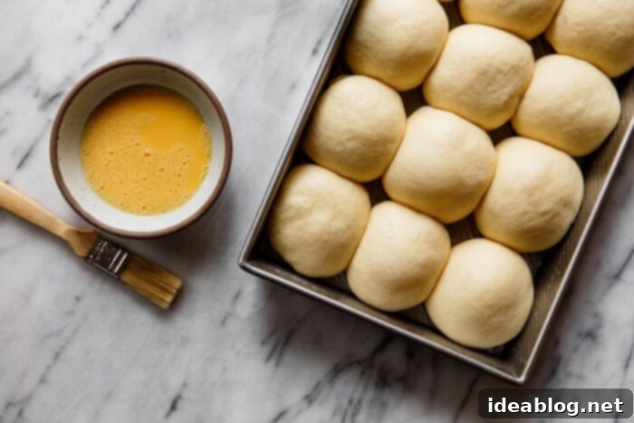 Ultimate Everything Dinner Rolls 15 Brushing the proofed dinner rolls with egg wash before adding seasoning.