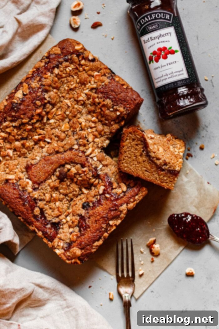 Rustic Raspberry Hazelnut Crumb Bake 2 A beautifully sliced Hazelnut Raspberry Crumb Cake, showcasing layers of moist cake, bright raspberry fruit spread, and a crunchy hazelnut topping.