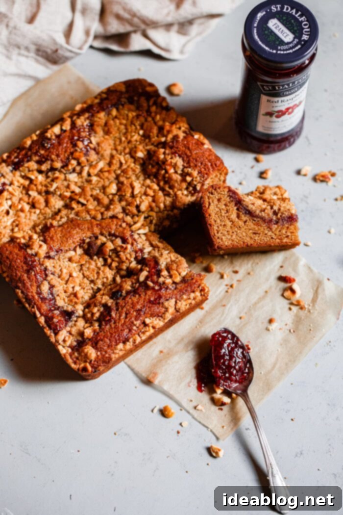 Rustic Raspberry Hazelnut Crumb Bake 18 A perfectly sliced piece of Hazelnut Raspberry Crumb Cake, revealing its moist interior, fruit layer, and crumbly top, ready to be enjoyed.