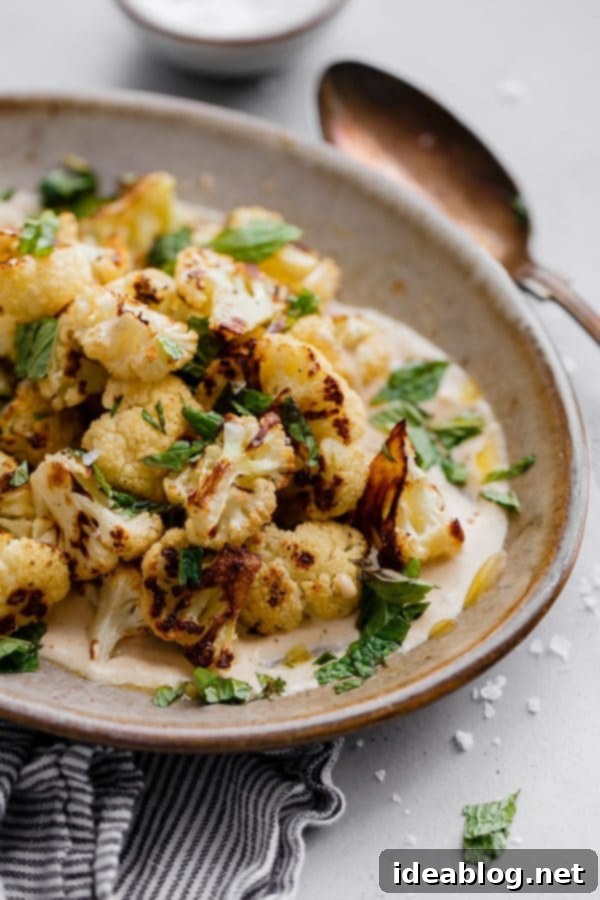 Roasted Cauliflower with Tahini and Mint - a delicious variation on a simple roasted cauliflower recipe! Caramelized and slightly spicy roasted cauliflower florets are served on a lemon tahini sauce and garnished with freshly torn mint leaves and flaky sea salt. #abeautifulplate #cauliflower #roastedvegetables #mint #tahini #sidedish #easyrecipes Roasted Cauliflower with Tahini and Mint, a simple elegant side