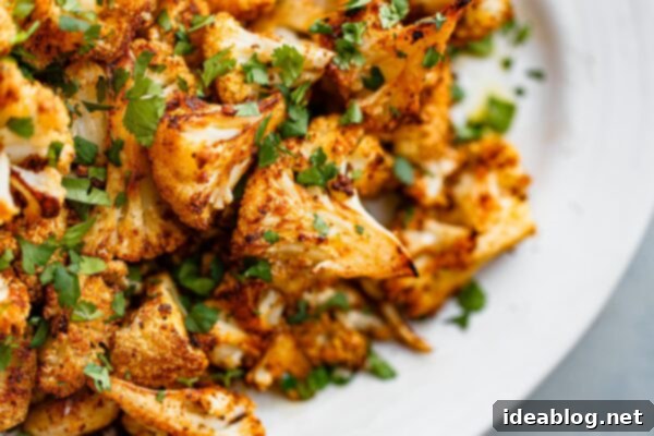 Roasted Cauliflower with Warm Spices 13 Easy spiced roasted cauliflower florets on a serving platter, garnished with lime and cilantro