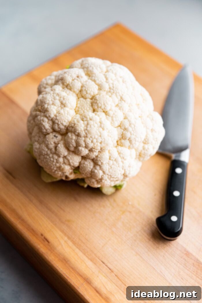 Roasted Cauliflower with Warm Spices 3 A whole head of fresh, unblemished cauliflower on a wooden cutting board, ready for preparation