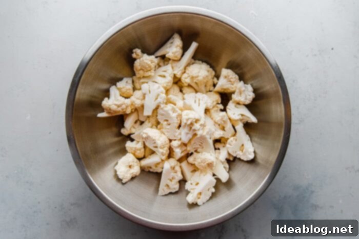 Roasted Cauliflower with Warm Spices 6 Cauliflower florets tossed with the vibrant spice and oil mixture in a large mixing bowl, ready for the oven