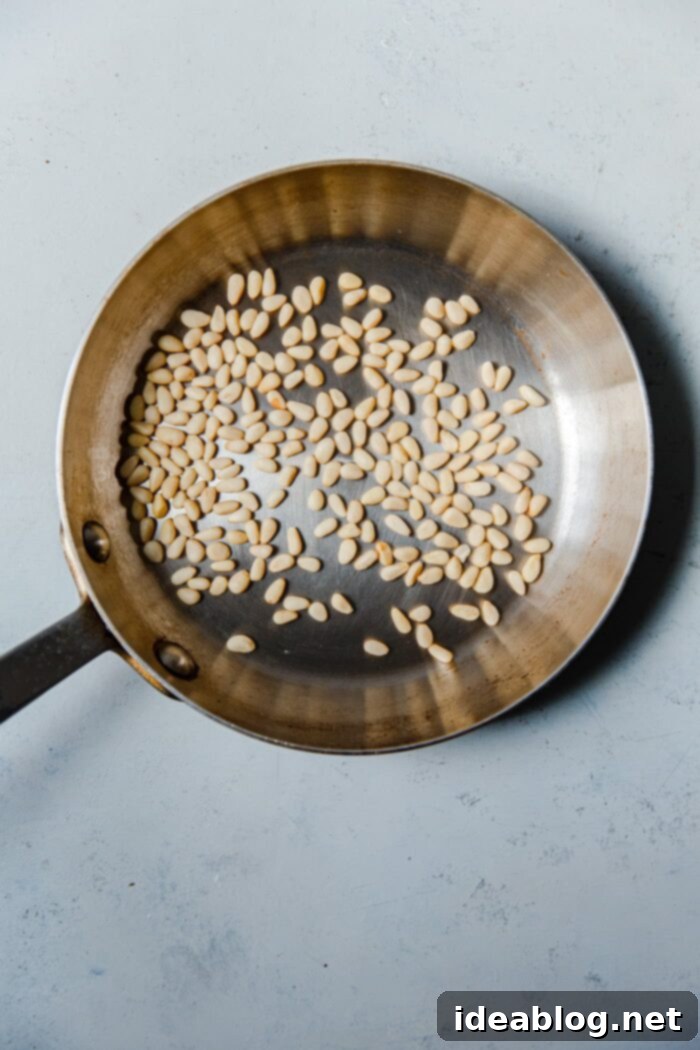 How to Perfectly Toast Pine Nuts 6 Raw Pine Nuts Being Stirred in a Dry Skillet on the Stovetop