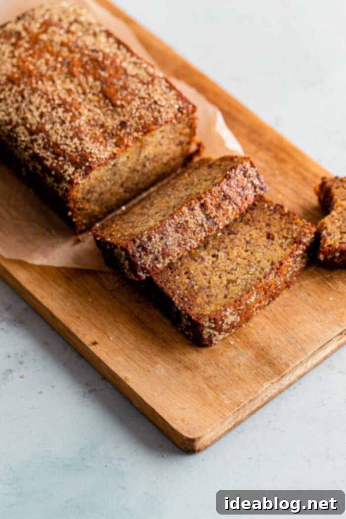 Ultimate Moist Banana Bread 3 A loaf of moist banana bread, freshly baked and sliced, resting on a wooden cutting board