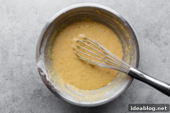 Ultimate Moist Banana Bread 8 Close-up of moist banana bread batter in a mixing bowl, showing its smooth consistency with flecks of banana