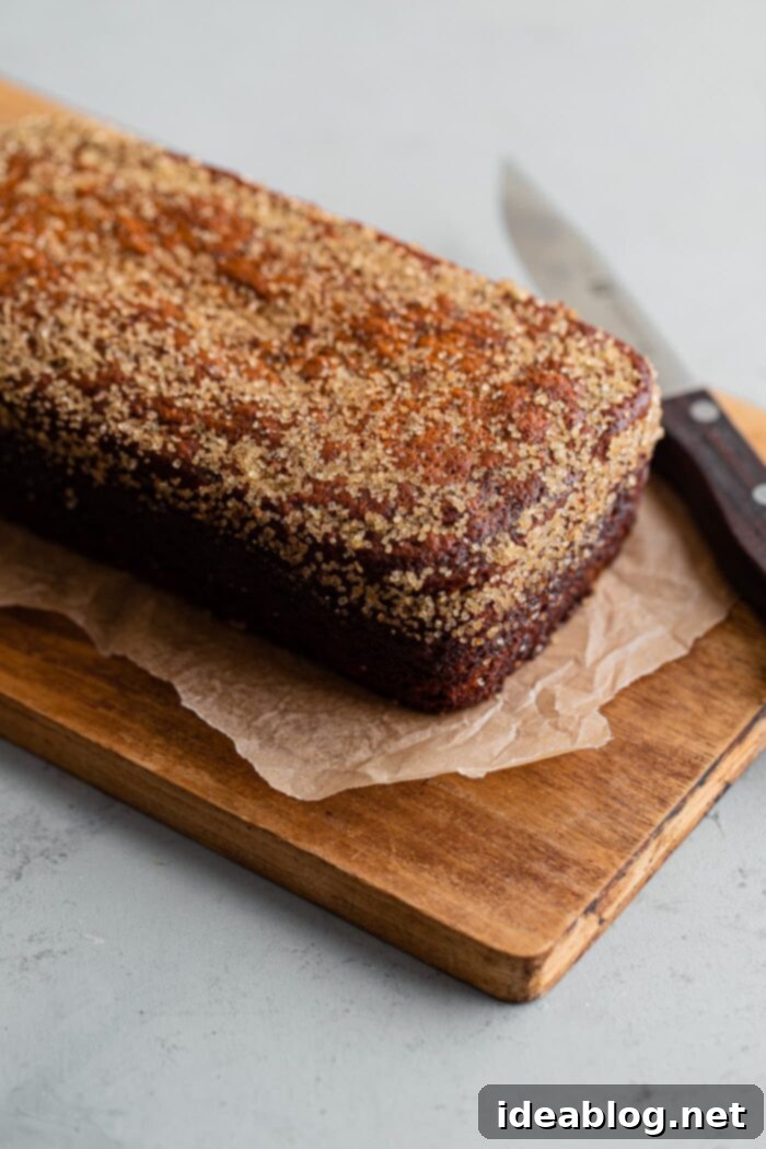 Ultimate Moist Banana Bread 10 A freshly baked, still warm loaf of moist banana bread on a wooden cutting board, ready to be sliced