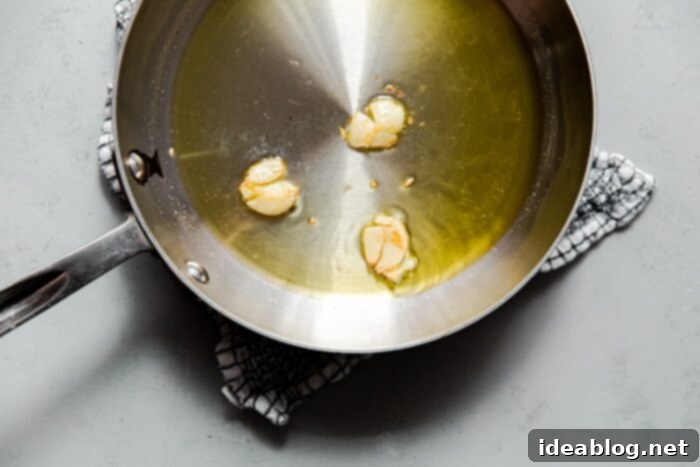 Irresistible Garlic Crunch 5 Smashed Garlic Cloves infusing in olive oil in a skillet