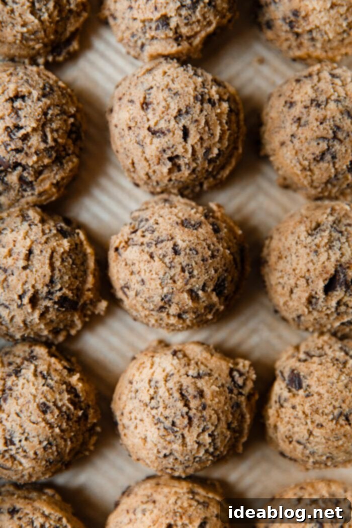 Ultimate Chocolate Chunk Cookies 3 Scoops of chocolate chunk cookie dough on parchment paper, ready for freezing or baking.