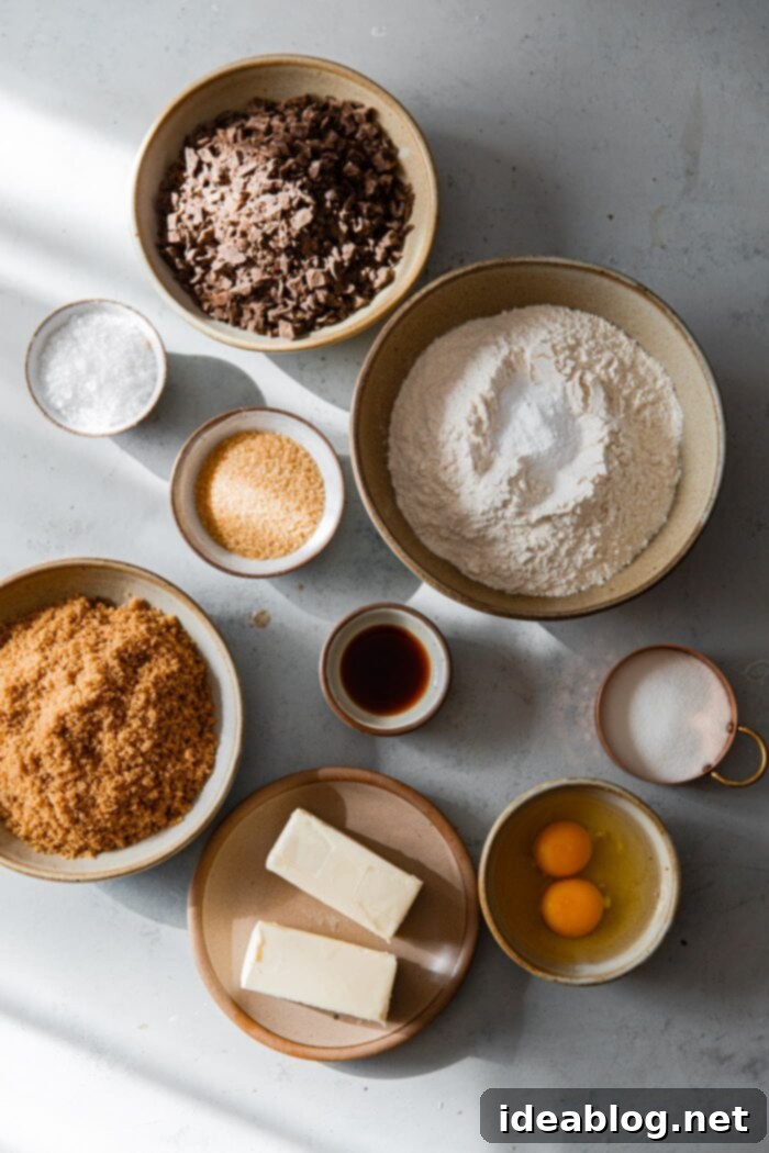 Ultimate Chocolate Chunk Cookies 5 Key ingredients for chocolate chunk cookies laid out, including butter, sugars, flour, eggs, chocolate, and vanilla.