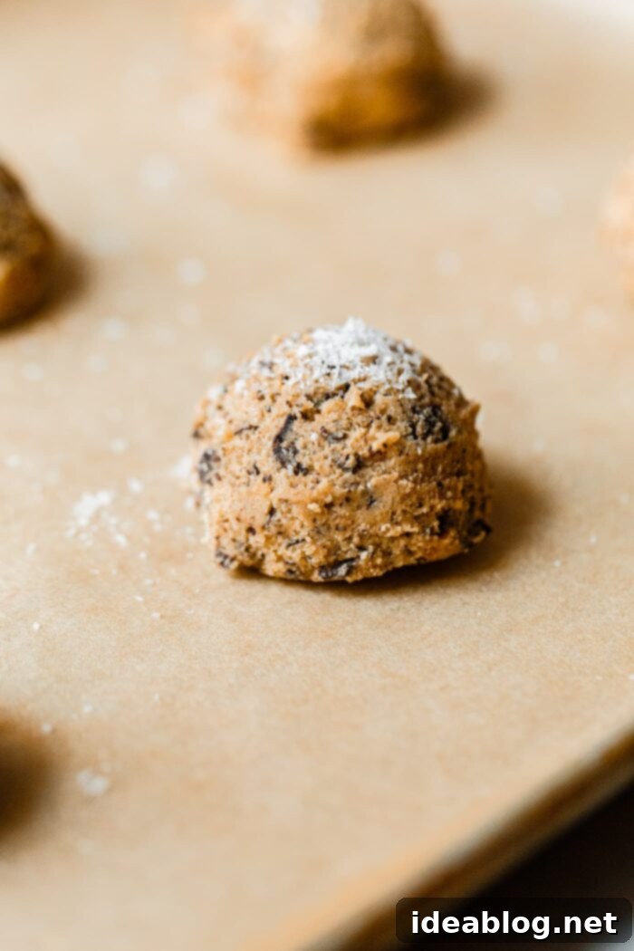 Ultimate Chocolate Chunk Cookies 8 Close-up of chocolate chunk cookie dough scoops, some sprinkled with Maldon salt, before baking.