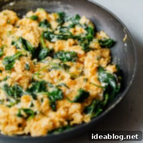Fluffy Cheesy Eggs with Fresh Greens 10 Cheesy Scrambled Eggs with Greens in Skillet, close-up