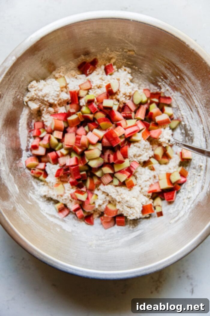 Zesty Orange Glazed Rhubarb Scones 6 Mixing scone dough with rhubarb pieces in a bowl before shaping.