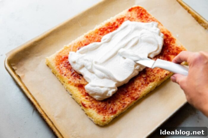 Festive Flag Dessert 9 Strawberries being layered over whipped cream on a sponge cake