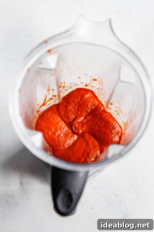 English Title Authentication 2 The rich, dark red mixture of blended ancho chiles, fire-roasted tomatoes, and aromatics in a high-powered blender, ready to be reduced for the soup base.