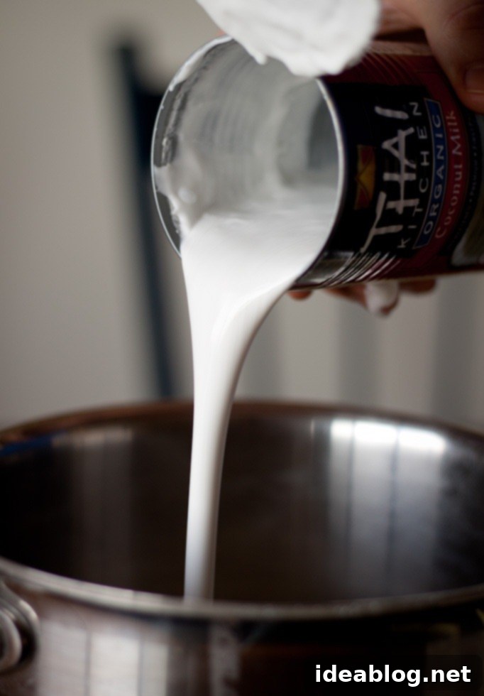 Vanilla Coconut Lemongrass Escape 5 Thick, creamy full-fat coconut milk being poured from a can into a saucepan