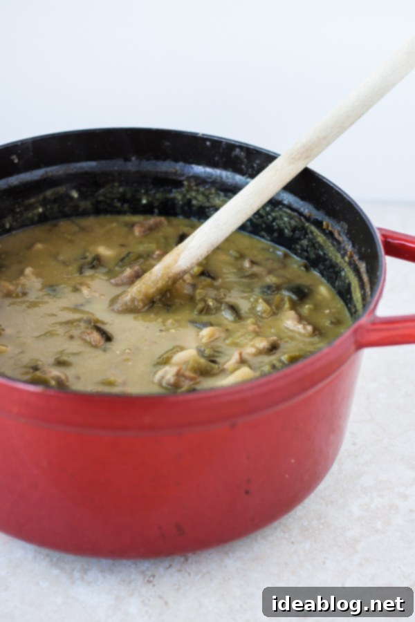 Chile Verde with Pork 4 Green Pork Chili simmering in a large, heavy Dutch oven on a stovetop, showcasing the rich green color.