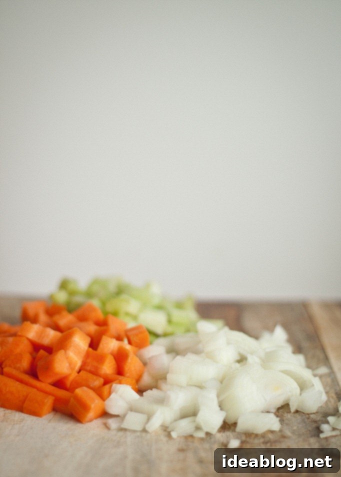 Tender Chicken Braised in Red Wine and Tomato Sauce 3 Fresh mirepoix (onions, carrots, celery) on a cutting board, essential for braised chicken flavor